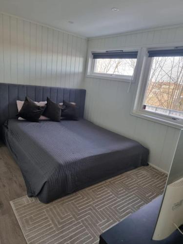 una camera da letto con un grande letto con due finestre di Cosy room with luxurious bathroom a Flateby