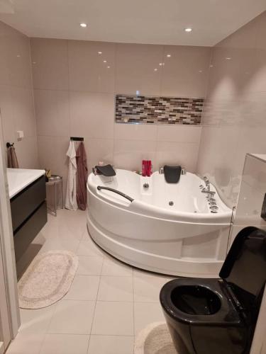 a large white bathroom with a tub and a toilet at Cosy room with luxurious bathroom in Flateby