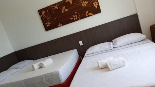 two beds in a room with white sheets and pillows at Apartamento em Resort in Barreirinhas