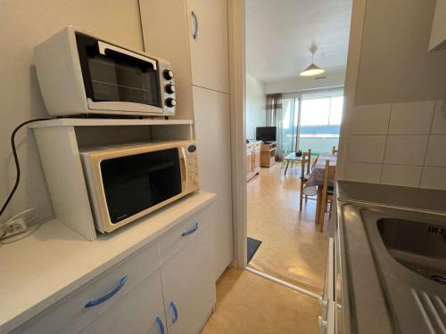 un micro-ondes posé sur un comptoir dans une cuisine dans l'établissement Appartement cosy proche plage avec balcon et vue mer - FR-1-224C-48, à Saint-Hilaire-de-Riez