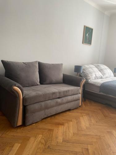 um sofá sentado numa sala de estar ao lado de uma cama em Friendly Apartment em Cracóvia
