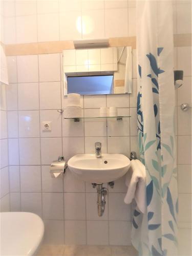 a white bathroom with a sink and a toilet at Pension Schwartzwirt in Neusiedl am Steinfelde
