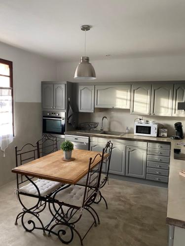 Il comprend une cuisine avec une table et des chaises en bois. dans l'établissement Villa Domélia, à Villelaure