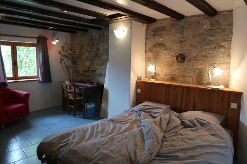 une chambre avec un lit et un mur en pierre dans l'établissement La maison d' Anne , nature et convivialité ..., à Albas