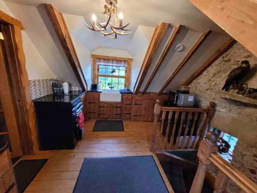 a kitchen with a staircase and a dining room with a chandelier at Baidland Escapes 2 bedroom cottage With hot tub in Dalry
