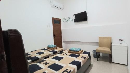 a room with two beds and a chair in it at Taras Homestay in Seribu
