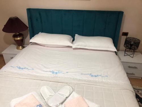 uma cama com uma cabeceira azul e dois sapatos brancos em Alva Room's em Gjirokastër