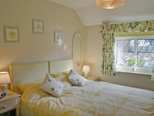 a bedroom with a bed with two pillows and a window at Lace Cottage in Ashbourne