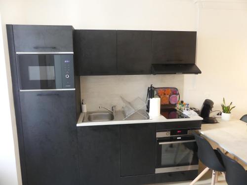 a kitchen with black cabinets and a sink at Superbe Maison Rénovée en Centre-ville in Saint-Pierre-dʼOléron