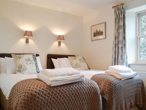 a bedroom with two beds with towels on top of them at Cobblers Cottage in Ripley