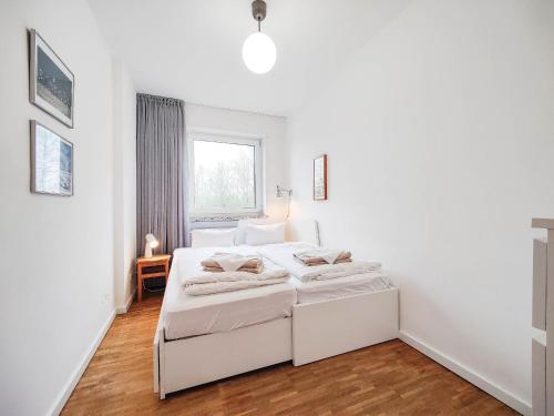 a white bedroom with a bed and a window at Wohnung Berlin in Norderney