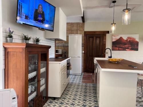 a kitchen with a refrigerator and a tv on the wall at Casa rural en plena naturaleza Lic UVTR1524 in Eguíllor