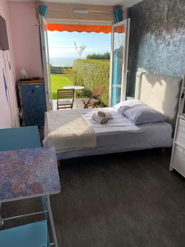 une chambre avec un lit et une grande fenêtre dans l'établissement Studio cosy et terrasse-jardin superbe vue mer, à Trouville-sur-Mer