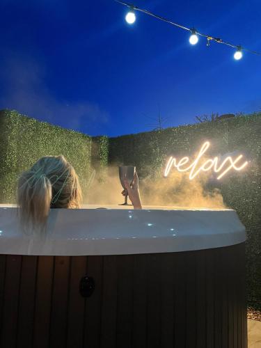 a woman sitting in a bath tub with a sign at Birch Cottage in Tenby