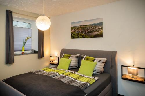 トラーベン・トラーバッハにあるFerienwohnung Ginsterbergのベッドルーム(緑の枕とソファ付)