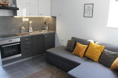 ein Wohnzimmer mit einem Sofa und einer Küche in der Unterkunft Cozy Corners in Nin