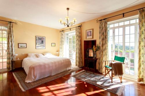a bedroom with a bed and large windows at Vila Chácara Flora em Malveira da Serra in Alcabideche