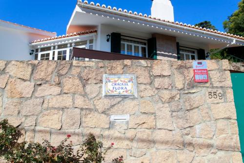 a house behind a stone wall with signs on it at Vila Chácara Flora em Malveira da Serra in Alcabideche