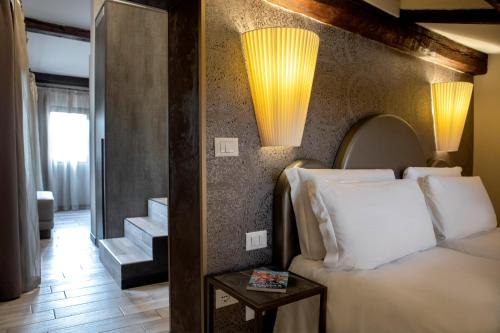 威尼斯的住宿－Alle Guglie Boutique Hotel，卧室配有一张床,墙上有两盏灯
