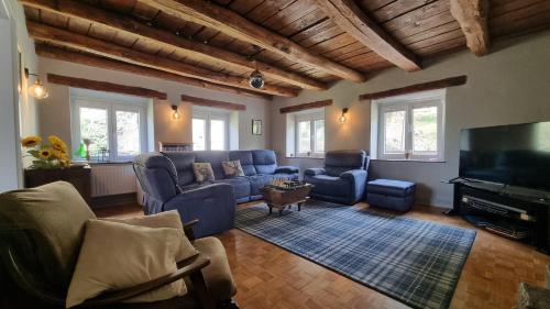 a living room with blue furniture and a flat screen tv at Hisa Brdo Guesthouse in Tolmin