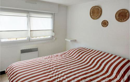 1 Bedroom Beautiful Apartment In Cucq في كوسيك: غرفة نوم بسرير مخطط ونوافذ