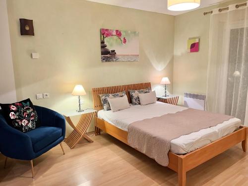 ein Schlafzimmer mit einem Bett und einem blauen Stuhl in der Unterkunft Villa Romuald in Sainte-Maxime