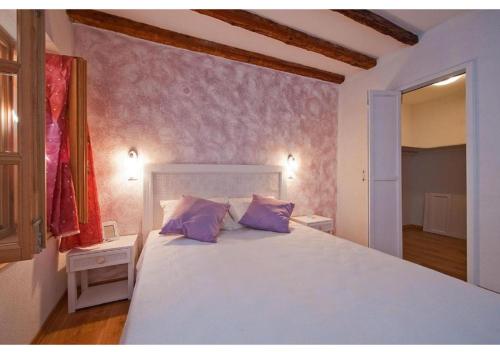 Un dormitorio con una gran cama blanca con almohadas moradas. en San Cristoforo Accommodations Rovinj - Garzotto, en Rovinj