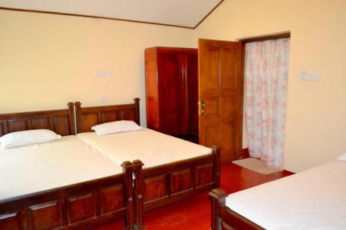 巴杜拉的住宿－Bogaspitiya Bungalow，一间卧室设有两张床,一扇门通往房间