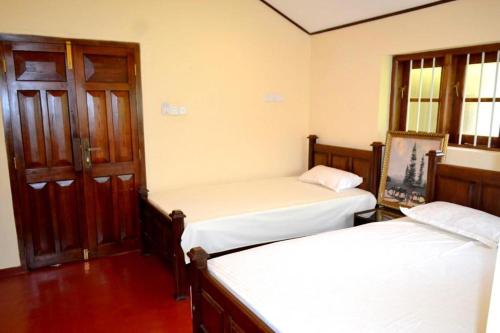 巴杜拉的住宿－Bogaspitiya Bungalow，客房设有两张床、一扇门和窗户。