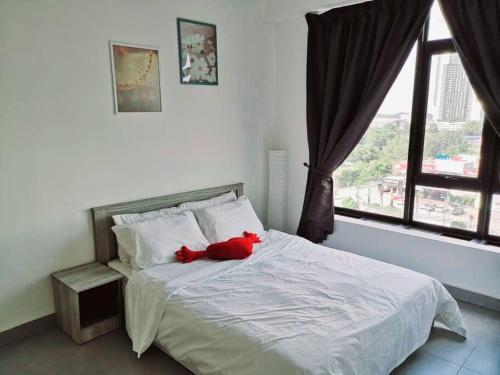 un animal de peluche rojo sentado en la parte superior de una cama en KA701-One Bedroom Apartment- Wifi -Netflix -Parking - Pool, 1002, en Cyberjaya