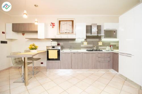 a kitchen with white cabinets and a table at La Casina Del 5 by TuscanyWeGo in Villa Bertolli