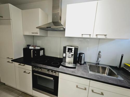 a kitchen with white cabinets and a sink and a microwave at Weinstadt Monteurwohnnung Ferienwohnung in Weinstadt