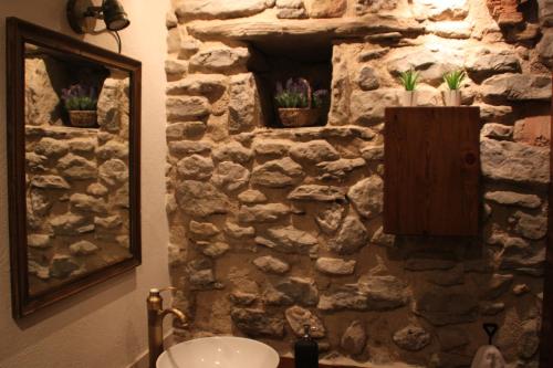 Łazienka z kamienną ścianą, umywalką i lustrem w obiekcie L'Urdet w mieście Sant Llorenc de Morunys