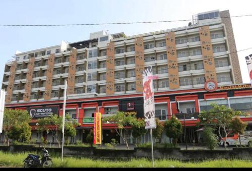 un grand bâtiment avec une moto garée devant lui dans l'établissement Student park apartment, à Seturan