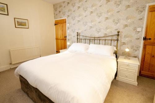 a bedroom with a large white bed with a wooden headboard at Skelwith Fold Cottage No.1 in Elterwater