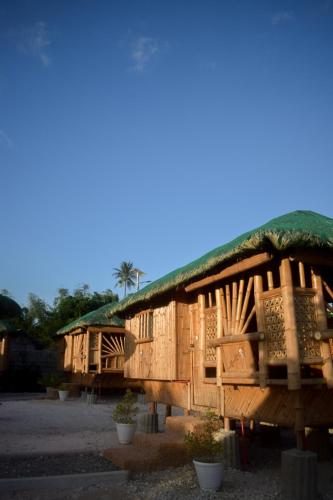 a wooden house with a green roof and some plants at GoOd Inn White Beach Moalboal in Cebu City