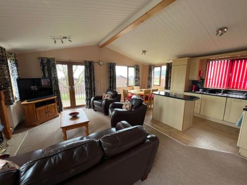 a large living room with couches and a kitchen at Getaway Lodge in Ilfracombe