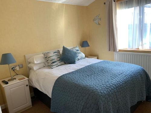 a bedroom with a bed with blue sheets and a window at Getaway Lodge in Ilfracombe