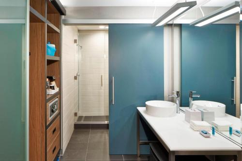 Łazienka z 2 umywalkami i niebieską ścianą w obiekcie Aloft Seattle Redmond w mieście Redmond