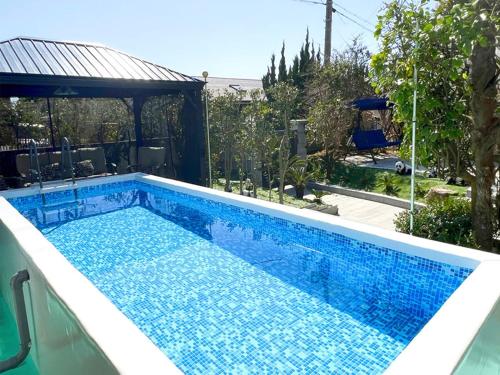 a swimming pool with blue tiles in a backyard at 海の眺め/プール付き/炭火BBQ(雨でも可能)/まるまる貸切別荘/最大13名/名勝千畳敷・三段壁近く in Shirahama