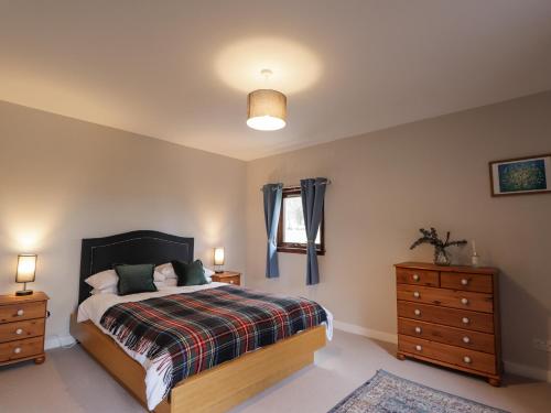 a bedroom with a bed and two dressers and a window at Fresh Fields in Dingwall