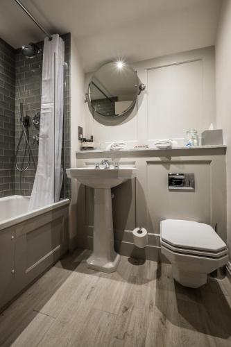 a bathroom with a sink and a toilet and a mirror at Coach & Horses Hotel in London