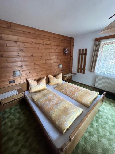 a bedroom with two beds and a wooden wall at Haus Gletscherblick in Gschnitz