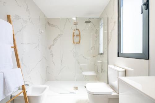 La salle de bains blanche est pourvue d'une douche et de toilettes. dans l'établissement Apartment with ocean view and parking, à Funchal