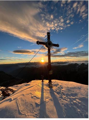 une croix au sommet d'une montagne enneigée dans l'établissement Haus Gletscherblick, à Gschnitz