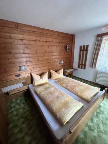 a bedroom with two beds and a wooden wall at Haus Gletscherblick in Gschnitz