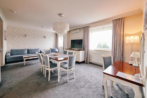 a living room with a table and chairs and a couch at Biały Dom Henlex Hotel Restauracja in Poznań