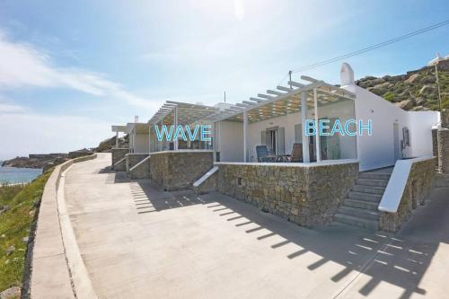 a house with a stone wall next to the ocean at 1Path Wave Mykonos Super Paradise Beach House in Mýkonos City