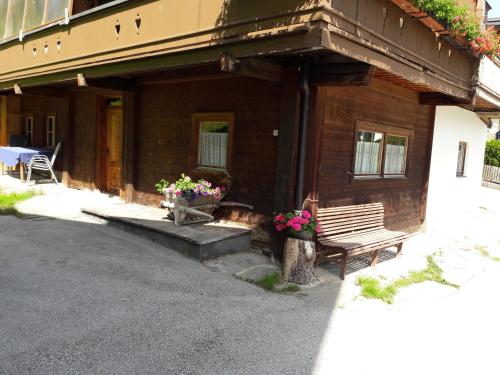 a wooden house with a bench and flowers on it at Haus Bacher in Tux