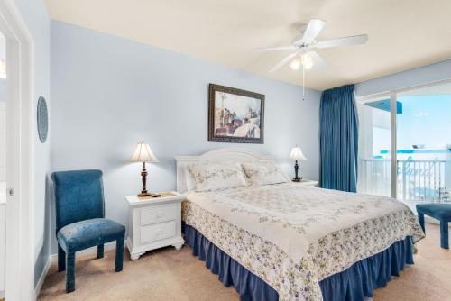 a bedroom with a bed and two chairs and a window at Destin West Gulfside #608 in Fort Walton Beach